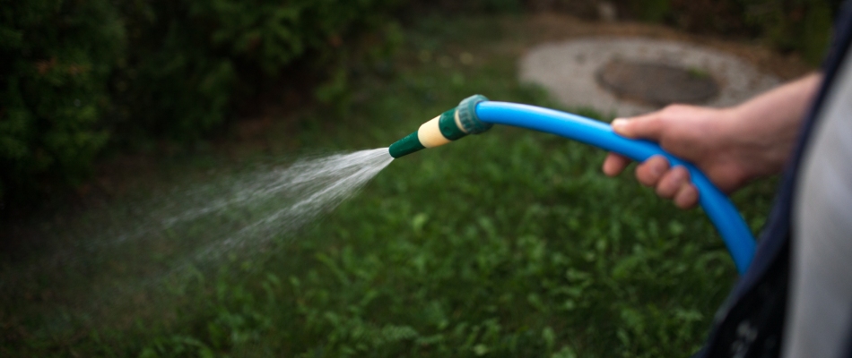 A man spraying liquid fertilizer on a lawn in Round Rock, TX.