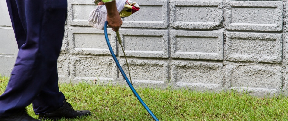 Professional applying perimeter pest control around a home in Austin, TX.